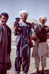 Three men, one holding infant and baby goat, photo by Françoise Foliot, 1974-1975, Creative Commons Attribution-Share Alike 4.0 International license